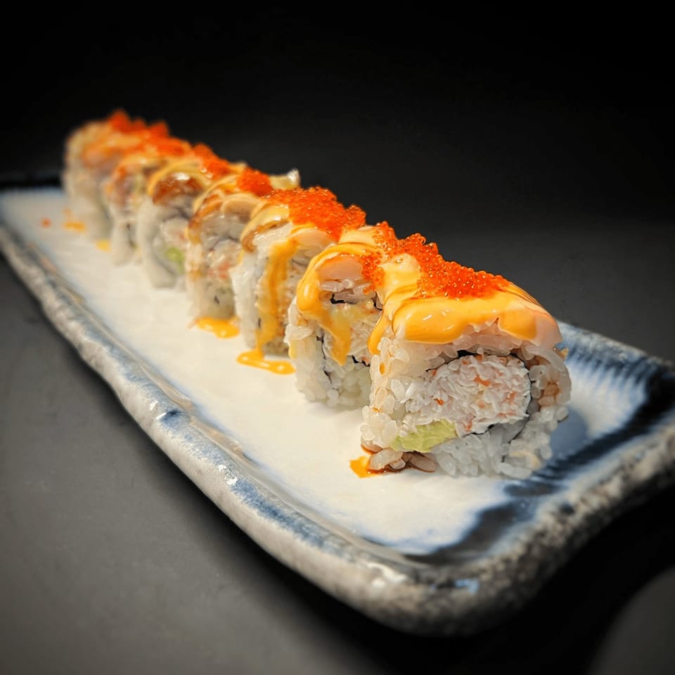 Tokyo Dori Sushi and Grill's sushi roll with orange roe and yellow sauce on a white plate.