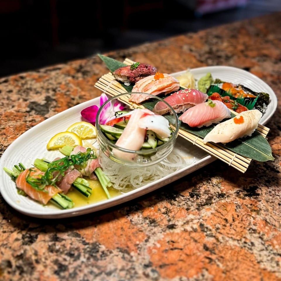 A white platter of Tokyo Dori sushi and sashimi, including salmon, tuna, and yellowtail.